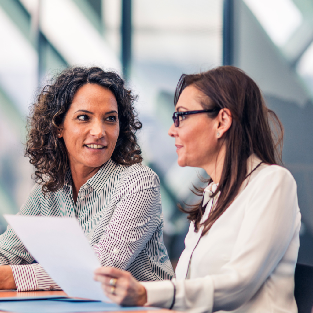 Two women sit at a table in a professional setting